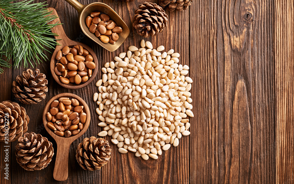 Fototapeta premium Pine nuts or cedar nuts with cedar cone on a wooden background.