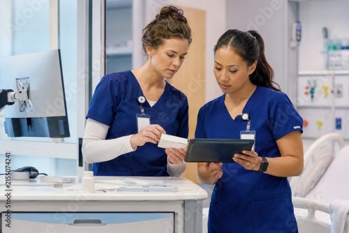Two female nurses reviewing patient records on a digital tablet in a modern clinic