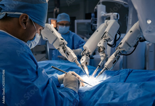 Male surgical specialist operating advanced medical robotic arm technology in high tech operating room
