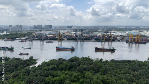 An aerial view of Cat Lai Port, a major container port in Ho Chi Minh City, Vietnam. Cargo ships are moored along the Saigon River.