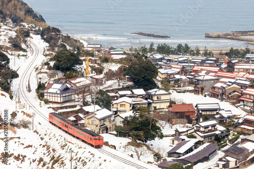 фотографія 雪が残っているとはいえ穏やかな冬景色では山陰本線のタラコ色がよく目立つ