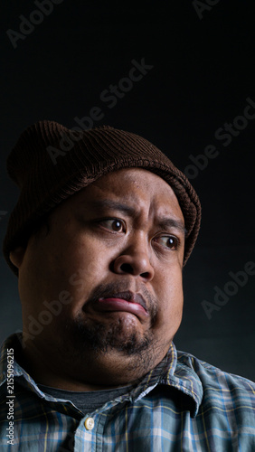 Bild auf Leinwand A close up portrait of a young Asian male from Indonesia Southeast Asia showing a disgusted and disappointed facial expression against a dark background