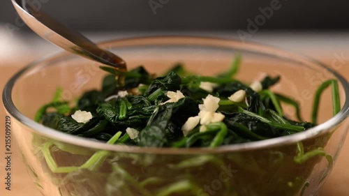 Pouring sesame oil into mixing bowl with Korean spinach salad (Sigeumchi namul), slow motion