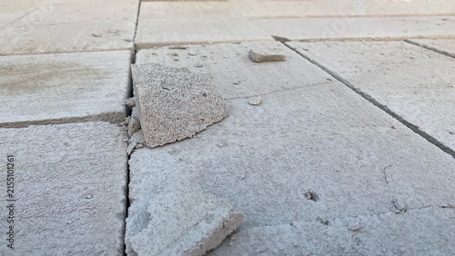 Canvas Print A cracked and damaged concrete paving surface with fragments of material, displaying a rough texture and details of damage caused by usage and weathering