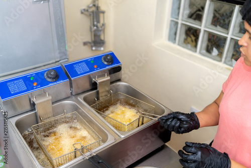 Young woman frying chicken in commercial kitchen