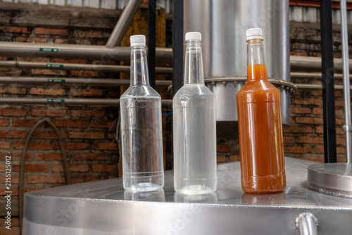 Glass bottles showcasing fresh tequila distillates and raw fermented must inside an authentic Mexican distillery. Highlight on the production process.