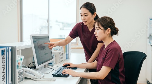 ナースステーションで電子カルテの操作指導とOJT研修を受ける新人看護師