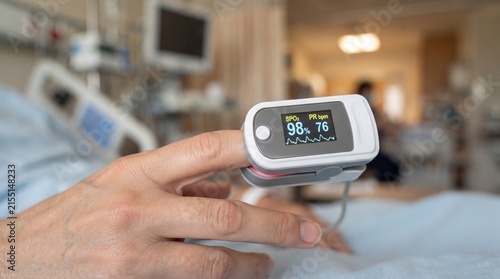 pulse oximeter on patient finger measuring blood oxygen saturation level and heart rate in hospital room close up