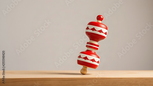 A red and white roly-poly toy wobbling upright on wood, symbolizing resilience.