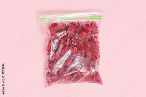 Raspberry berry in cellophane zip-lock bags on pink background close-up top view.