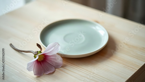 Celadon plate with mugunghwa flower on light wooden surface, mindful arrangement and everyday beauty concept