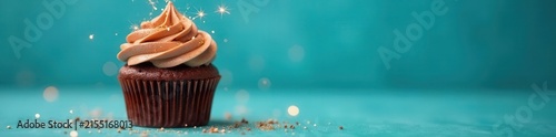 Single chocolate cupcake, golden sparkler, bright blue backdrop, candle, sprinkles