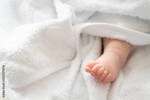 Foto Infant's imprint: baby foot shyly emerging from white fabric