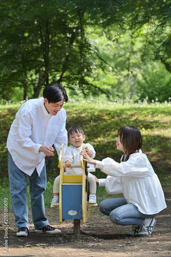 公園のスプリング遊具で遊ぶ若いファミリー