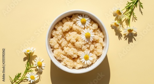 Bowl of healthy oatmeal porridge with fresh chamomile flowers on pastel background