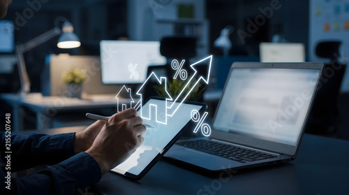 Businessman analyzing real estate market growth and rising mortgage interest rates on digital tablet in office at night with glowing icons