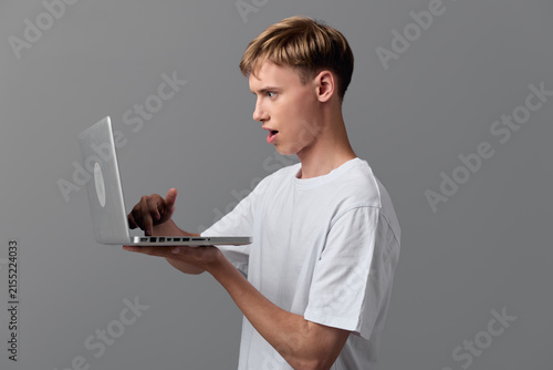 Obraz na plátne Surprised man holds a laptop aloft, exploring technology and digital learning wi