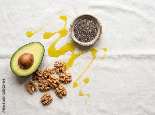 Healthy food ingredients including avocado walnuts and chia seeds with olive oil drizzle.