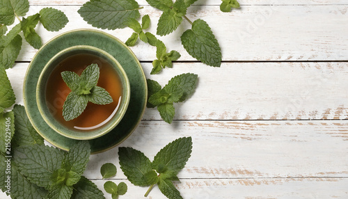 Fresh Mint Tea with Green Cup and Leaves on White Wooden Table
