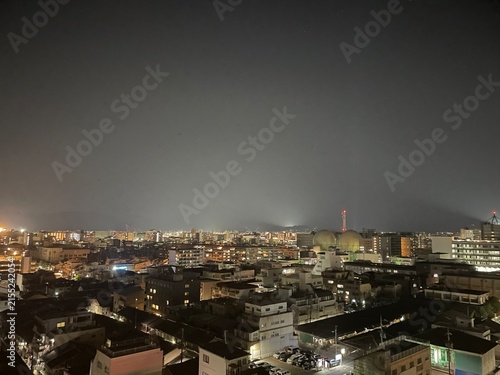 Tapety artystyczne 見下ろす夜の街並みと輝く住宅街の明かり、遠くの山々のシルエット