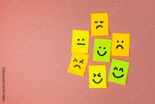 Colorful sticky notes with drawn emoticon faces expressing various emotions on a pink background. Customer feedback, mental health, evaluation, reviews concept.
