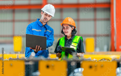 Male engineer and female worker using laptop at production line in steel factory teamwork