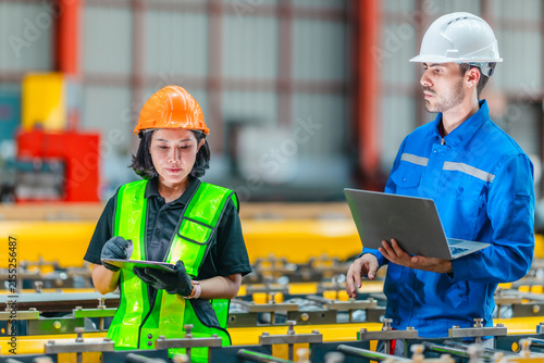 Male engineer and female worker using laptop at production line in steel factory teamwork