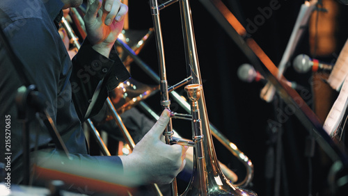 Fotografie Closeup of hands adjusting trombone slide under stage lights