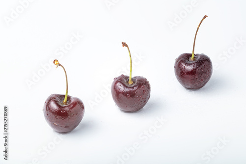 Three Ripe Cherries with Water Drops on White Background