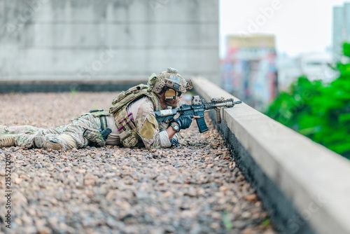 Fotografie Military tactical team takes firing position behind rooftop cover during urban o