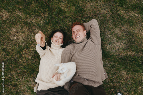 Foto Cheerful outdoor couple lying on grass, sharing a warm blanket, wearing cozy swe