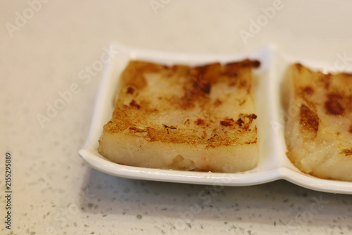 Photography Pan-fried radish cakes served neatly on a white ceramic plate.