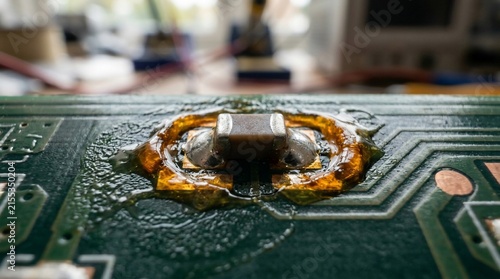 Macro view of an electronic circuit board with a soldered component and residue.