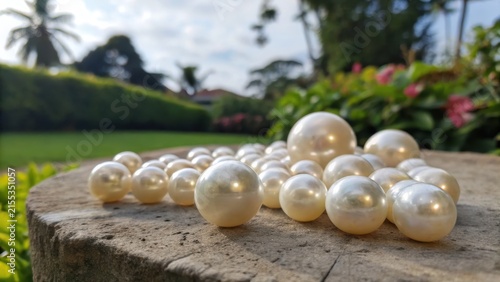 Collection of Lustrous Pearls Scattered on Stone Surface Outdoors
