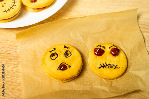 Two pumpkin shaped cookies on baking parchment close up