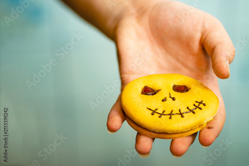 Hand holding a decorated Halloween pumpkin cookie close up