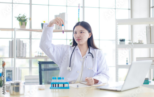 Asian young woman doctor holding look at test tubes red liquid of blood sample analysis medical vaccine innovation healthcare  scientist research technician development in laboratory hospital clinic.