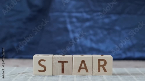 star, motivational word, laying out  by hand from letters on wooden cubes, slow motion
