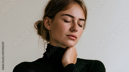 young woman holding her neck with soft overhead lighting