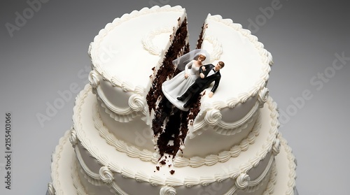 A split wedding cake with a bride and groom figurine falling into the crack representing divorce