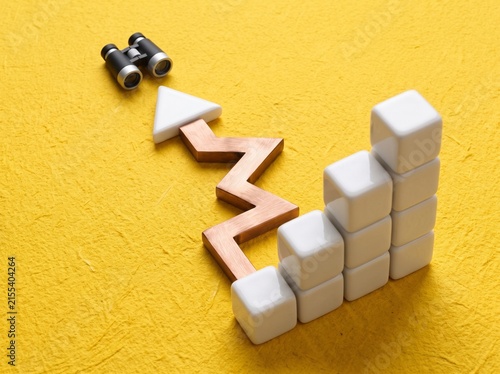 Business Growth Concept with Rising Wooden Arrow, White Blocks Bar Graph and Binoculars on Yellow Background