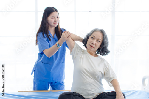 Asian female doctor physical therapist help senior woman back rehabilitation posture therapy in healthcare clinic professional patient care elderly recovery support wellness quality medical services.