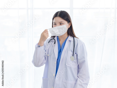 Asian woman doctor wearing protection face mask white medical coat in hospital clinic representing medical care infection flu disease prevention professional healthcare patient safety hygiene wellness