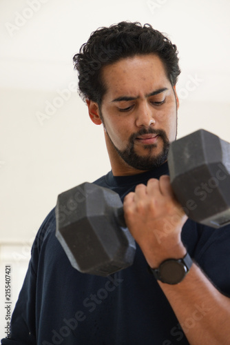 Fotografía African American man lifting dumbbell looking at weight wearing dark shirt and w