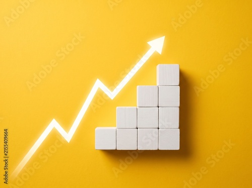 White Wooden Blocks Arranged in Rising Bar Graph Stairs with Upward Arrow on Yellow Background