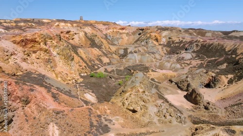 Parys Mountain Copper Mine, Amlwych, Anglesey, Wales, UK. Drone rise over main crater showing mineral colours with green hills becoming visible.