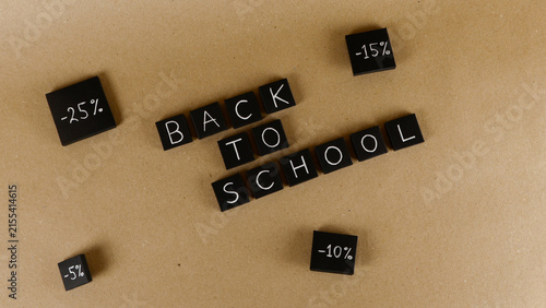 Fotografie Black square tiles spelling out Back to school are arranged on a light brown bac