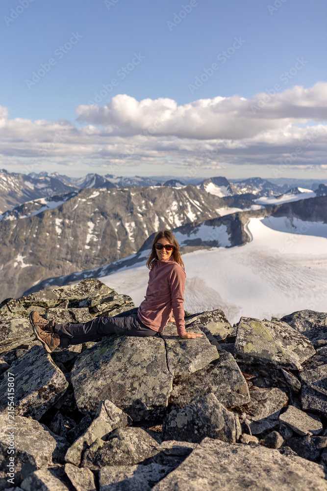 Fototapeta premium Beautiful european family with children and pet dog, hiking Galdhoppigen, 2469 m, the highest mountain peak in Norway on a beautiful sunny summer day, sunset, snow