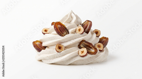 Distant shot of 5 to 10 dates and hazelnuts naturally resting on thick white cinnamon whipped cream
