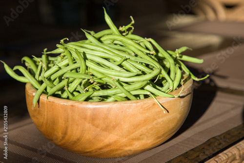 Green beans in a wooden bowl on a table. Close-up.